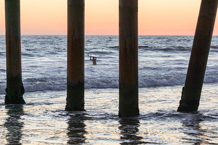 surfer-wading-out-twilight-through-pier-venice-beach